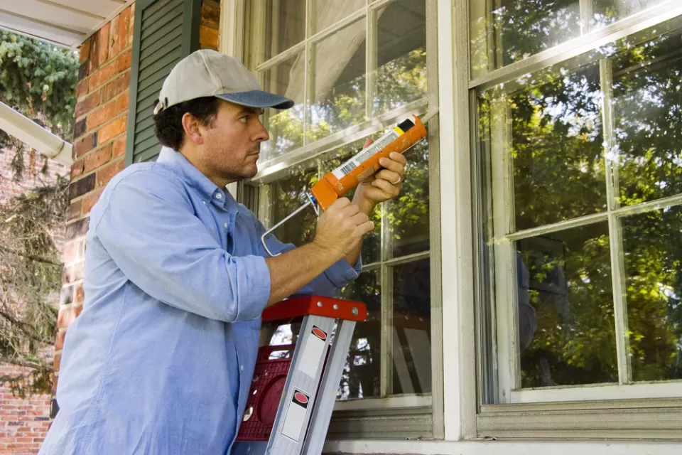 Worker caulking cracks in a home window